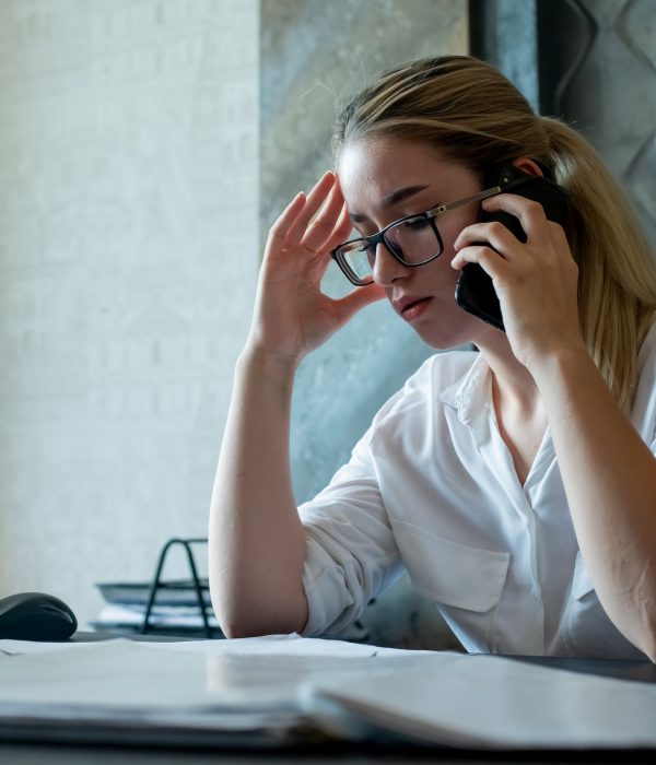 portrait of young office worker woman sitting at office desk with documents talking on mobile phone nervous and stressed working in office portrait of young office worker woman sitting at office desk with documents talking on mobile phone nervous and stressed working in office