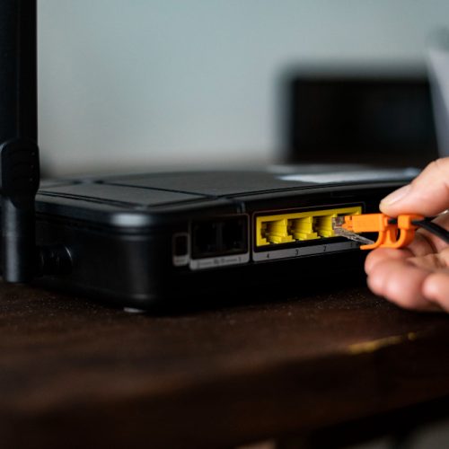 139544 A close up of a hand connecting an Ethernet cable to a VoIP phone router